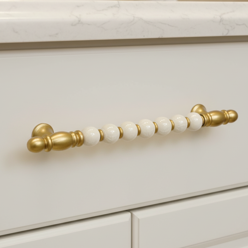 Cabinet handle with gold and white design on a white cabinet